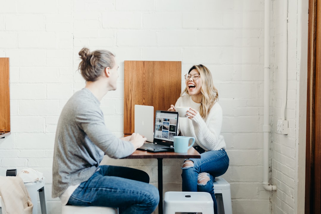 Two friends seated at a table, in conversation over coffee