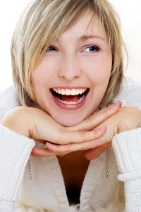 Blonde woman smiling and holding her hands under her chin