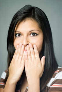 Woman with black hair covering her mouth with her hands