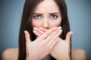 A brunette woman crossing her hands over her mouth