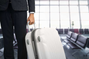 man rolling a white suitcase at the airport