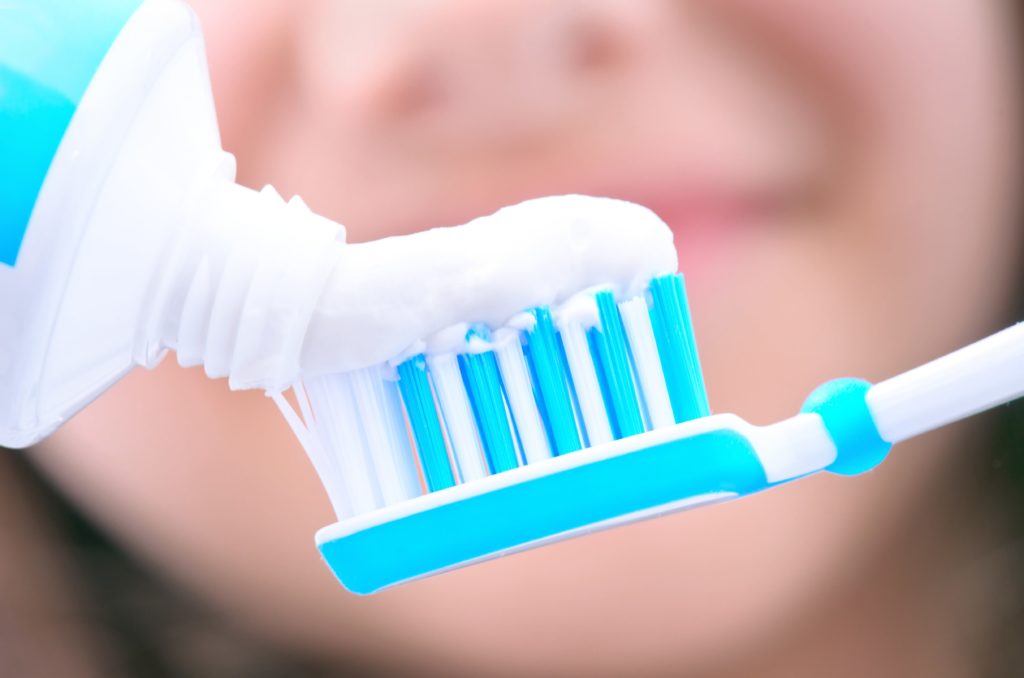 toothpaste being squeezed onto a toothbrush