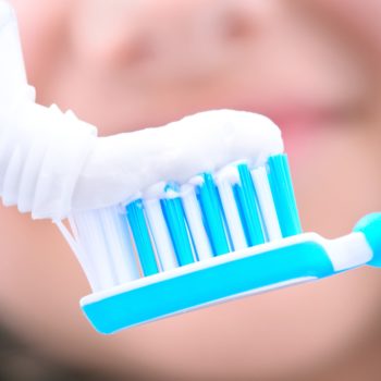 toothpaste being squeezed onto a toothbrush